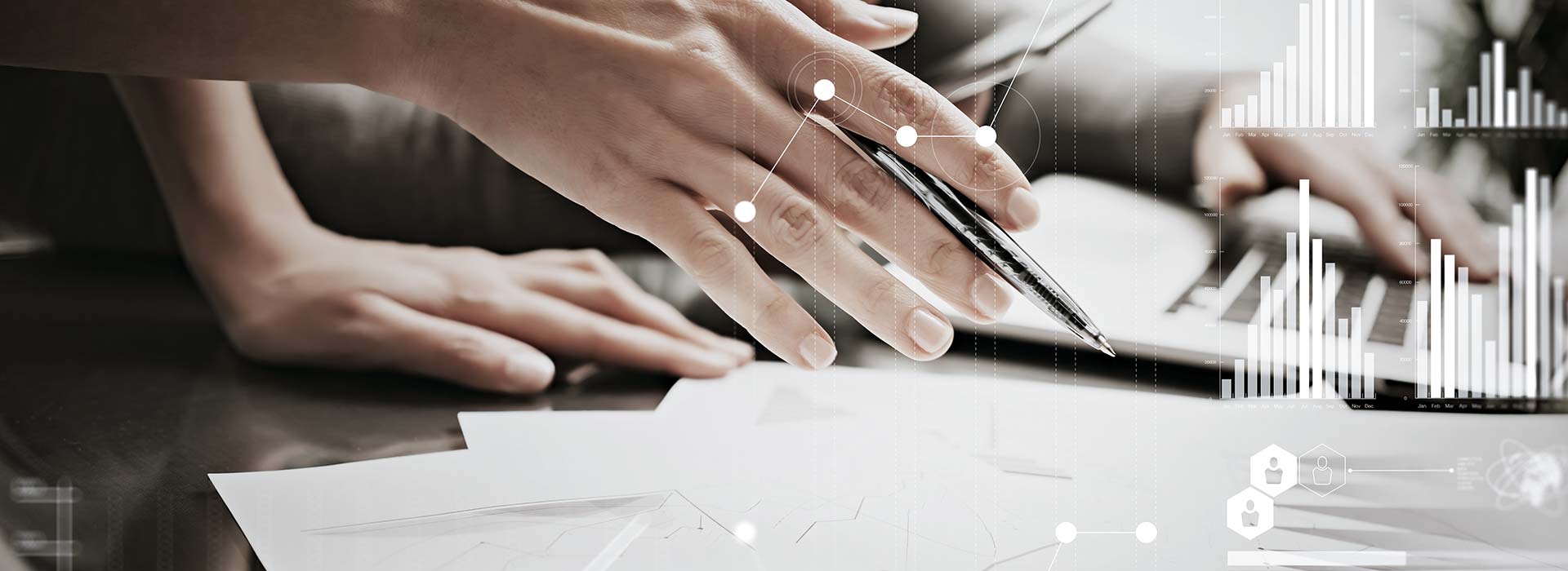 Eine Hand hält einen Stift über Dokumente mit Diagrammen, während im Hintergrund eine weitere Hand auf einer Laptop-Tastatur liegt. Überlagert sind digitale Grafiken mit vernetzten Punkten und Balkendiagrammen.