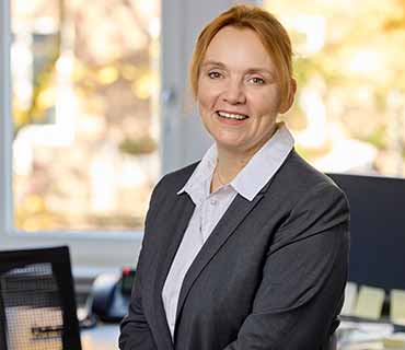 Einzelfoto von Anja Otersen in Business-Kleidung mit lächelndem Blick in die Kamera.